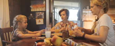 Raya, Nicolina und Wiebke sitzen am Frühstückstisch und Raya wird kritisch beäugt in Pelikanblut