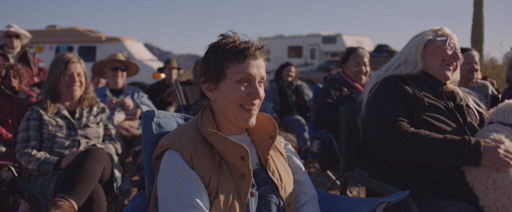 Frances McDormand als Fern sitzt im Camp mit anderen Nomaden auf Stühlen 