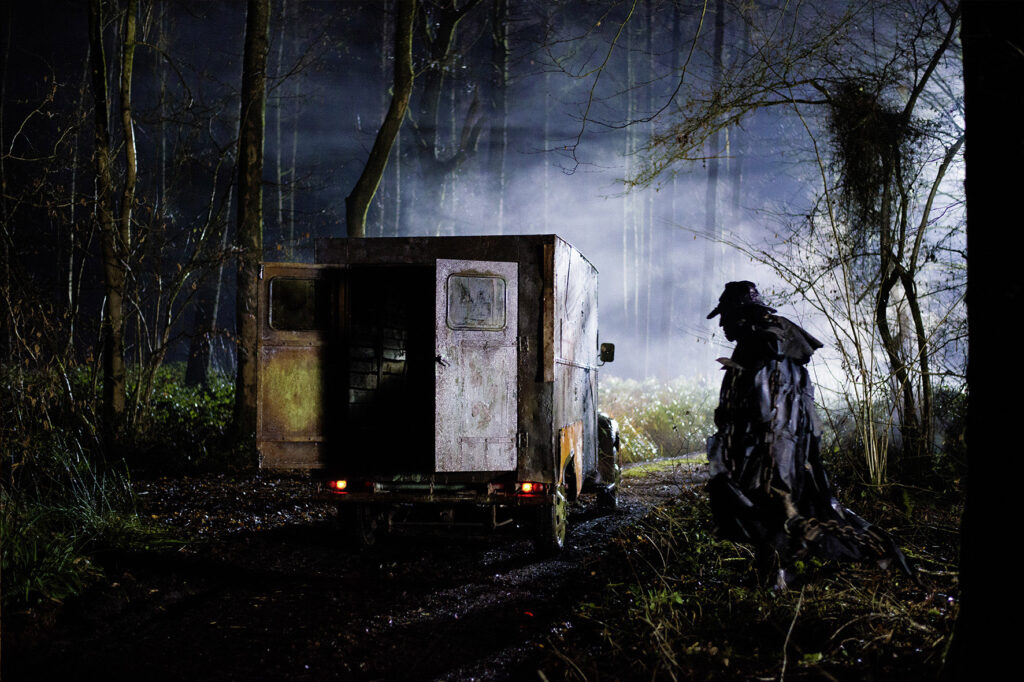 Der Creeper geht im Dunkeln auf seinen Truck zu. Die Türen des Laderaums sind offen. 