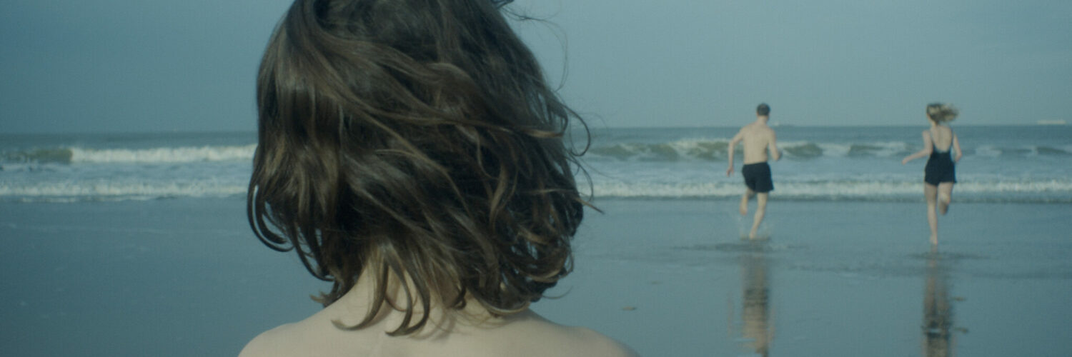Von hinten sieht man Max (Wanja Kube) der am Strand steht und Richtung Wasser, wo seine Schwester und sein Vater hinrennen.