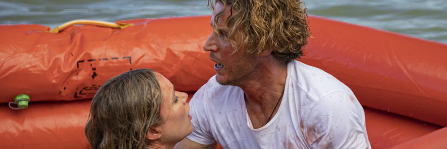 Charlie (Aaron Jakubenko) nimmt Kaz (Katrina Bowden) in auf dem Rettungsboot in den Arm, um sie vor dem gefährlichen Hai zu schützen.