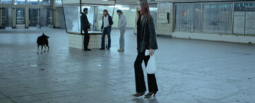 Christiane steht im weitestgehend verlassenen Bahnhof Zoo. Sie trägt eine weiße Plastiktüte bei sich und wirkt verunsichert.