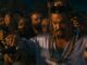 Ein Mann mit lilanem Satin-Hemd und Zöpfen sowie Bart steht vor einer Menschenmenge und hält zwei Waffen in seinen Händen hoch. Es der Schauspieler Jason Momoa als Dante Reyes in Fast & Furious 10.