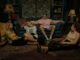 Die vier Hauptfiguren sitzen auf der Couch und auf dem Boden im Landhaus von Davis Eltern