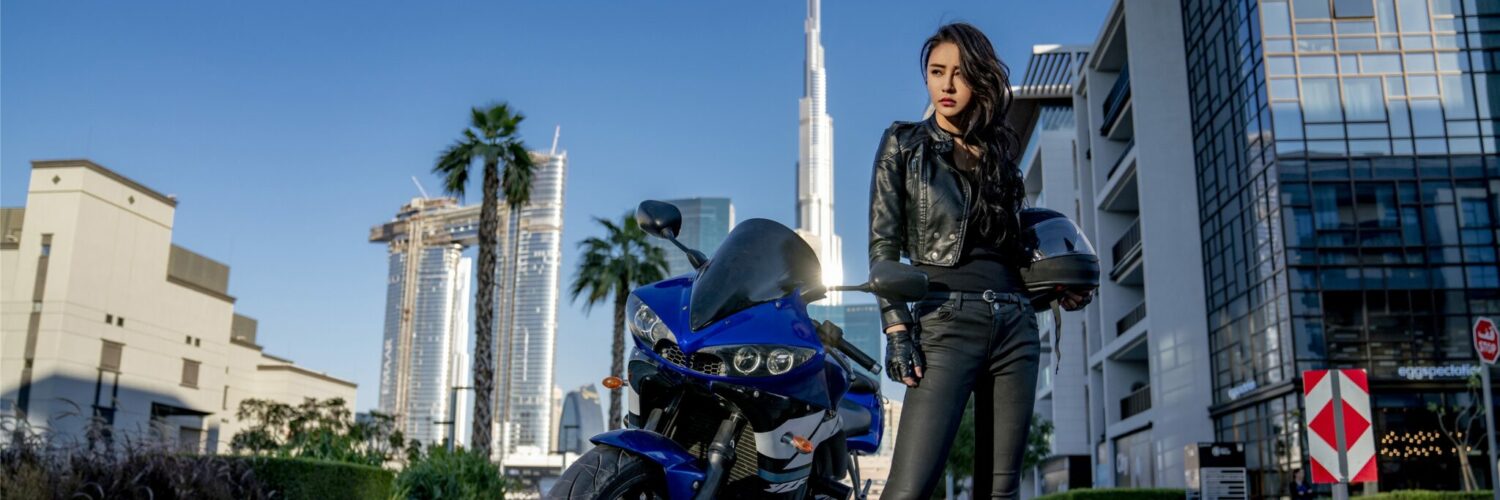 Eine junge, chinesische Frau in Leder-Kluft posiert neben ihrem Motorrad - Neu auf Sky im August 2021
