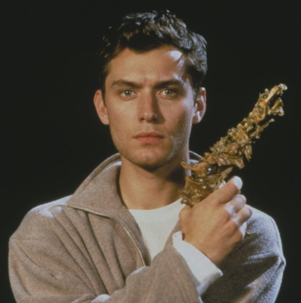 Jude Law posiert mit einer skurrilen, aus Knochen und Gräten gefertigten Waffe für eXistenZ