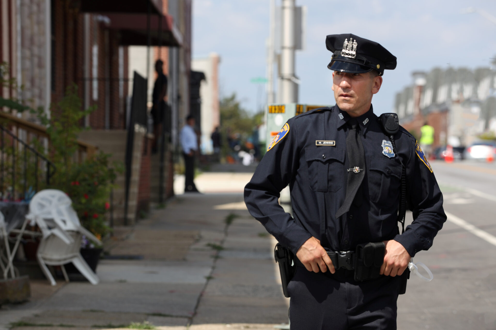 Jon Bernthal in Polizeiuniform mit Händen am Gürtel auf einer offenen Straße. We Own This City