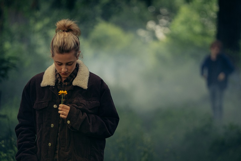 Eine junge Frau steht im Vordergrund, riecht an einer Blume; hinter ihr sieht man eine Gestalt im trüben Nebel - Neu auf Prime im August 2020