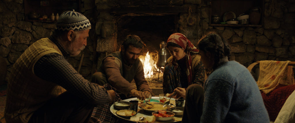 Veysel, Sevket, Reyhan und Havva sitzen im Kreis um einen Teller mit Essen