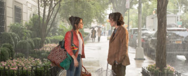 Shannon, gespielt von Selena Gomez, und Gatsby, gespielt von Timothée Chalamet, stehen im strömenden Regen auf der Straße. Gatsbys Schirm ist zusammengefaltet, die Nässe scheint beide nicht zu stören.
