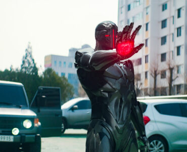 Der Guard (Androide) steht auf den Straßen Südkoreas und hat sein Ziel mit einem Energiestoß im Visier | Alienoid
