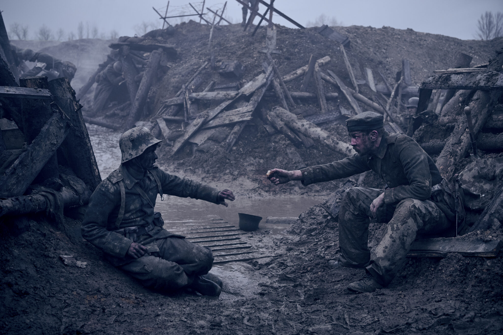 Ein Schützengraben in dem sich zwei Soldaten die Arme entgegenstrecken. Beide sind voller Dreck.