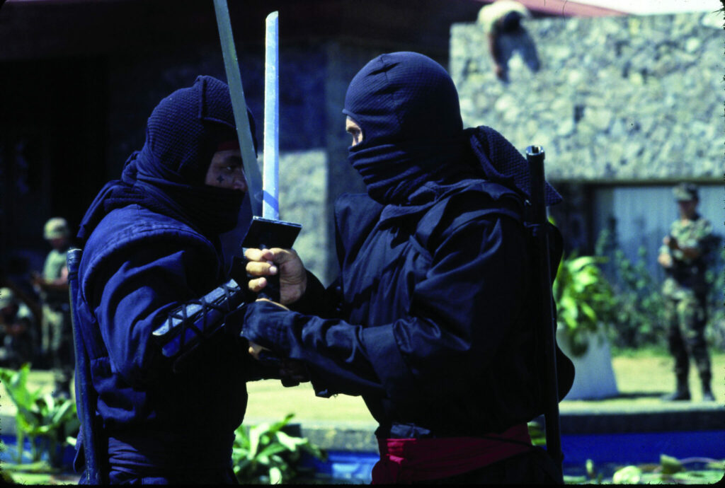 Zwei schwarzgewandete Ninjas kreuzen die Klingen ihrer Katanas - American Fighter