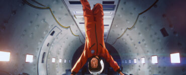 Ein Astronaut kopfüber in voller Montur innerhalb eines Raumschiffs schwebend.