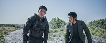 Die beiden Hauptfiguren Jo und Lee versuchen gemeinsam einen Behälter mit den Sprengköpfen zum Berg zu tragen. Beide sind gezeichnet von ihrem Verletzungen. Lee strömt das Blut von seinem Kopf links das Gesicht runter.