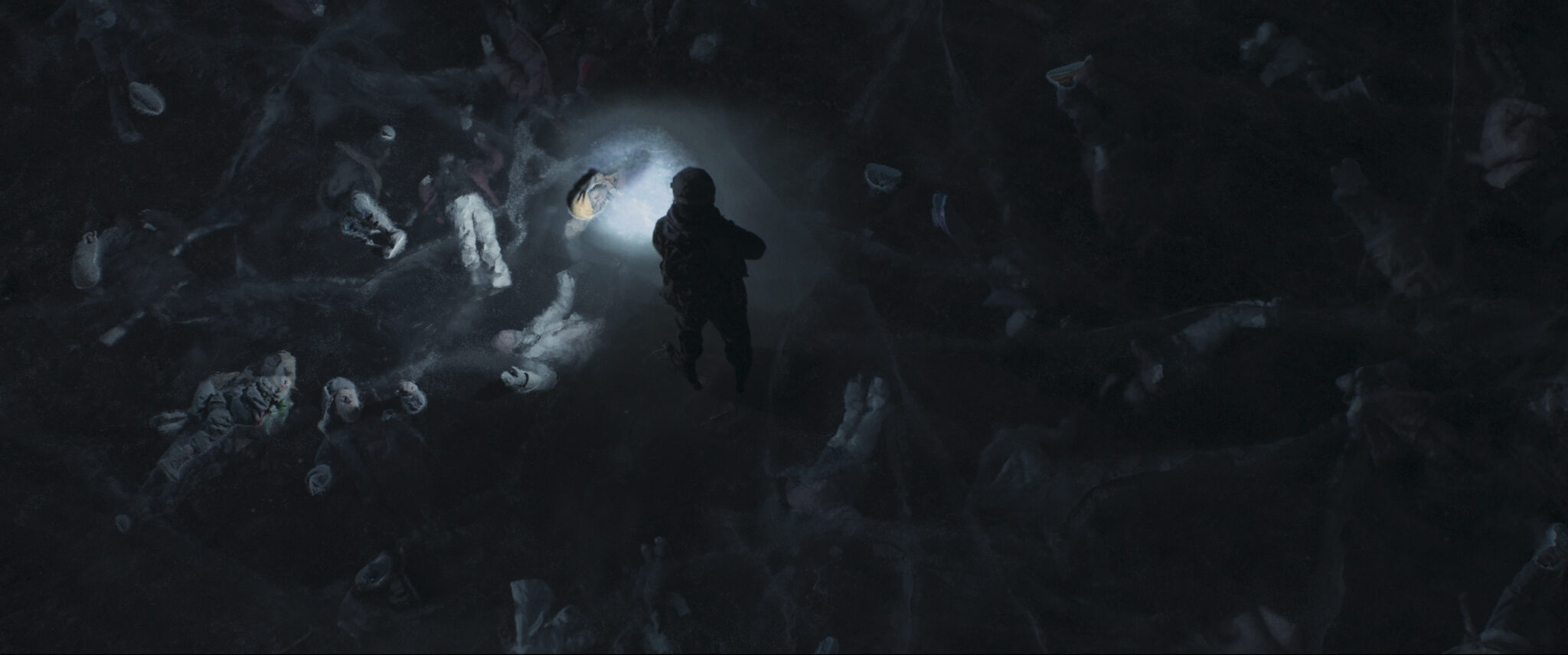 Ein zugefrorener See von oben im Dunkeln. Unter dem Eis sieht man angeleuchtet von einer Taschenlampe zahlreiche tote Körper.