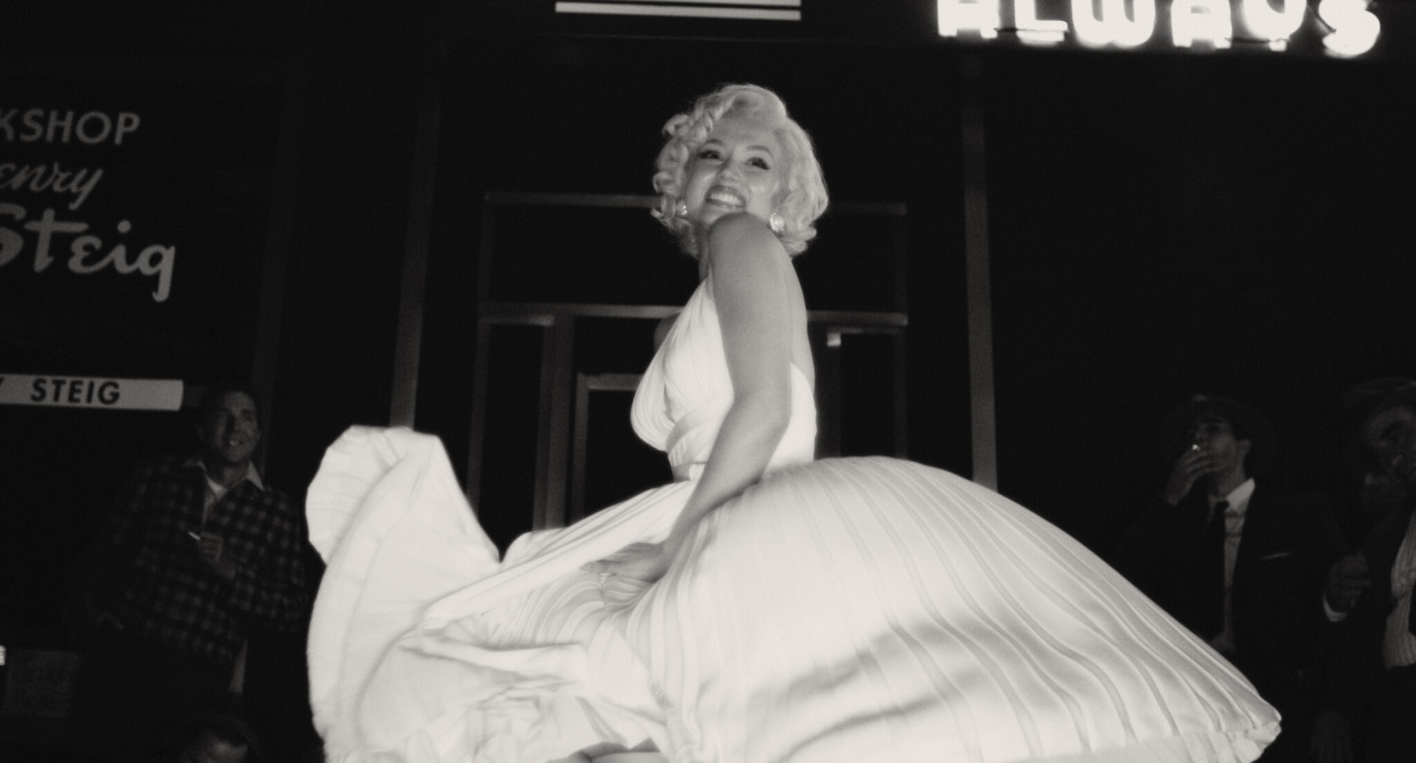Schwarzweißbild von Ana de Armas als Marilyn Monroe in weißem Kleid und lasziver Pose.