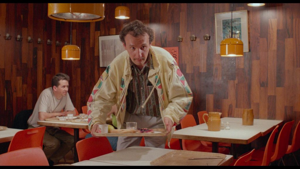Richard (Jean-François Gallotte) setzt sich mit einem Tablett an einen Tisch in einem Café | Baby blood