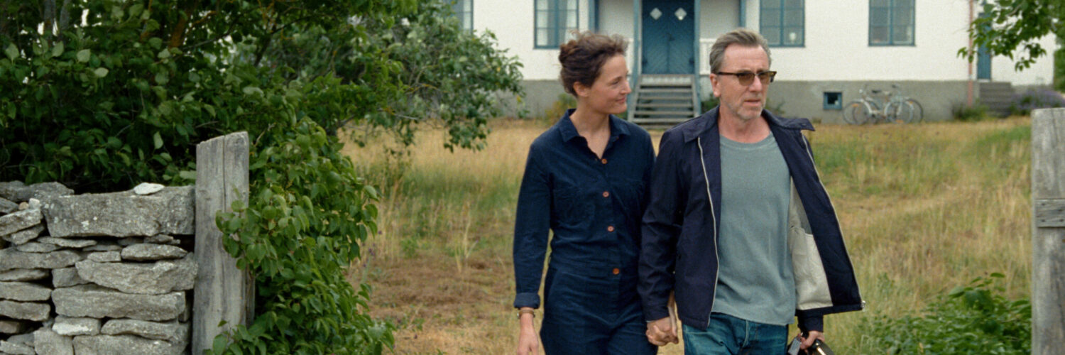 Christine (Vicky Krieps) und Tony (Tim Roth) gehen in Bergman Island gemeinsam auf der Insel Fårö spazieren.