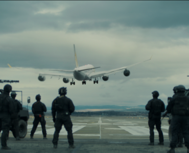 Das Bild aus Blood Red Sky zeigt ein Flugzeug von hinten über der Landebahn. Außerdem sieht man im Vordergrund einige bewaffnete Personen sowie zwei gepanzerte SUVs