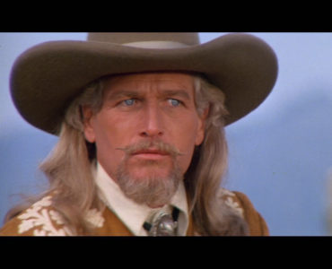 Paul Newman als Buffalo Bill in Nahaufnahme. Mit stilechtem Cowboy-Hut, imposanter Mähne, mächtigem Kinnbart und gezwirbeltem Schnauzer schaut er äußerst ernst drein.