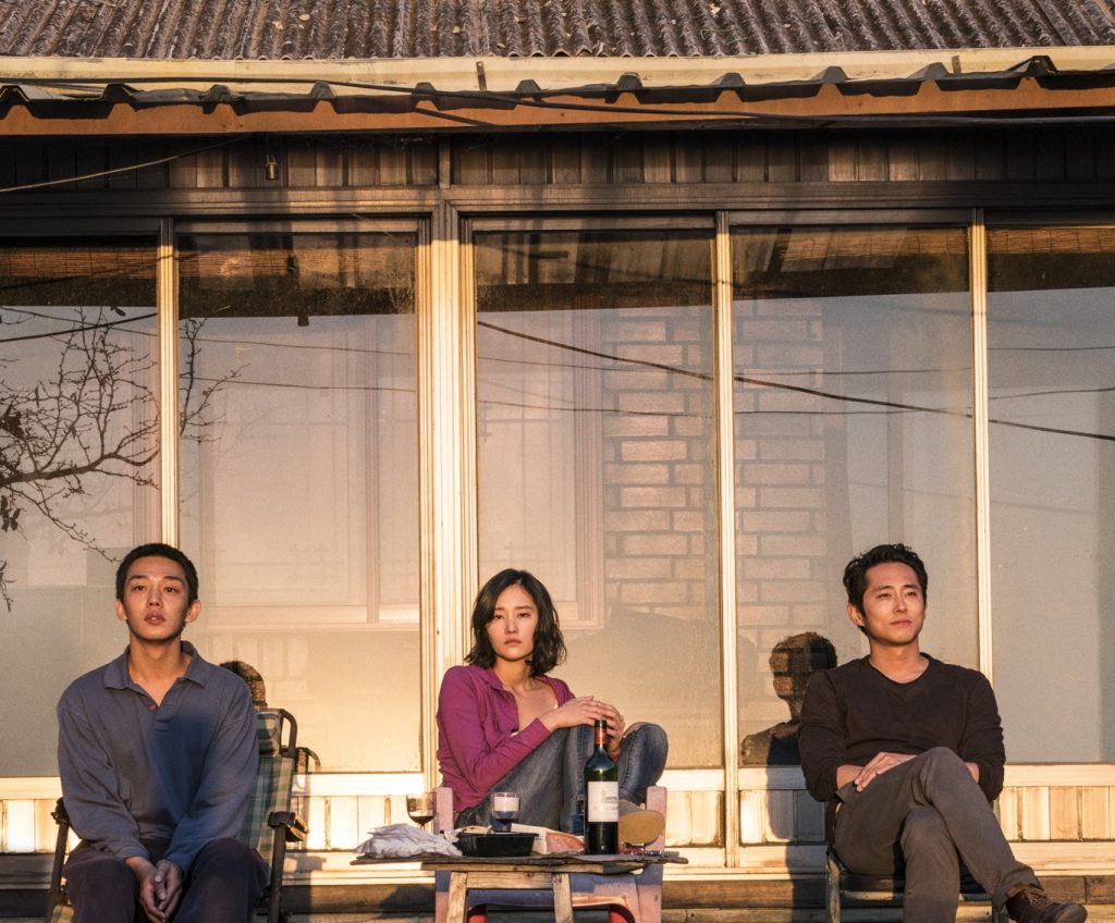 Lee Jong-soo (Ah-in Yoo), Shin Hae-mi (Jong-seo Jun) und Ben (Steven Yeun) beobachten nebeneinander sitzend einen Sonnenuntergang in Burning. © Capelight Pictures