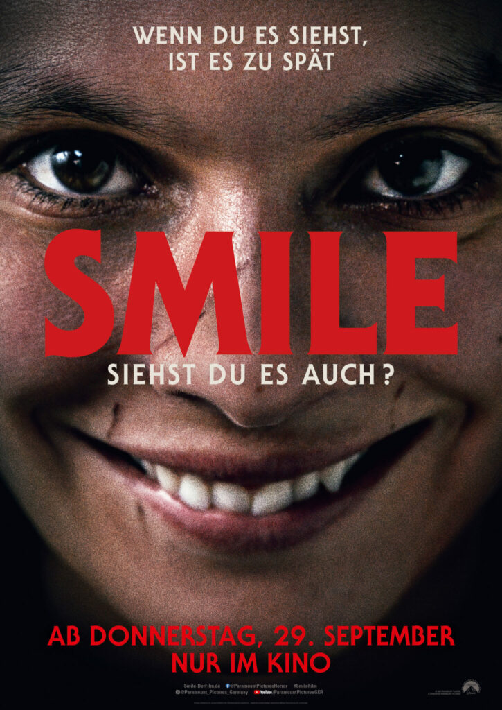 Auf dem Kinoplakat des Films Smile sieht man eine brünette junge Frau, die ein diabolisches Lächeln zeigt.