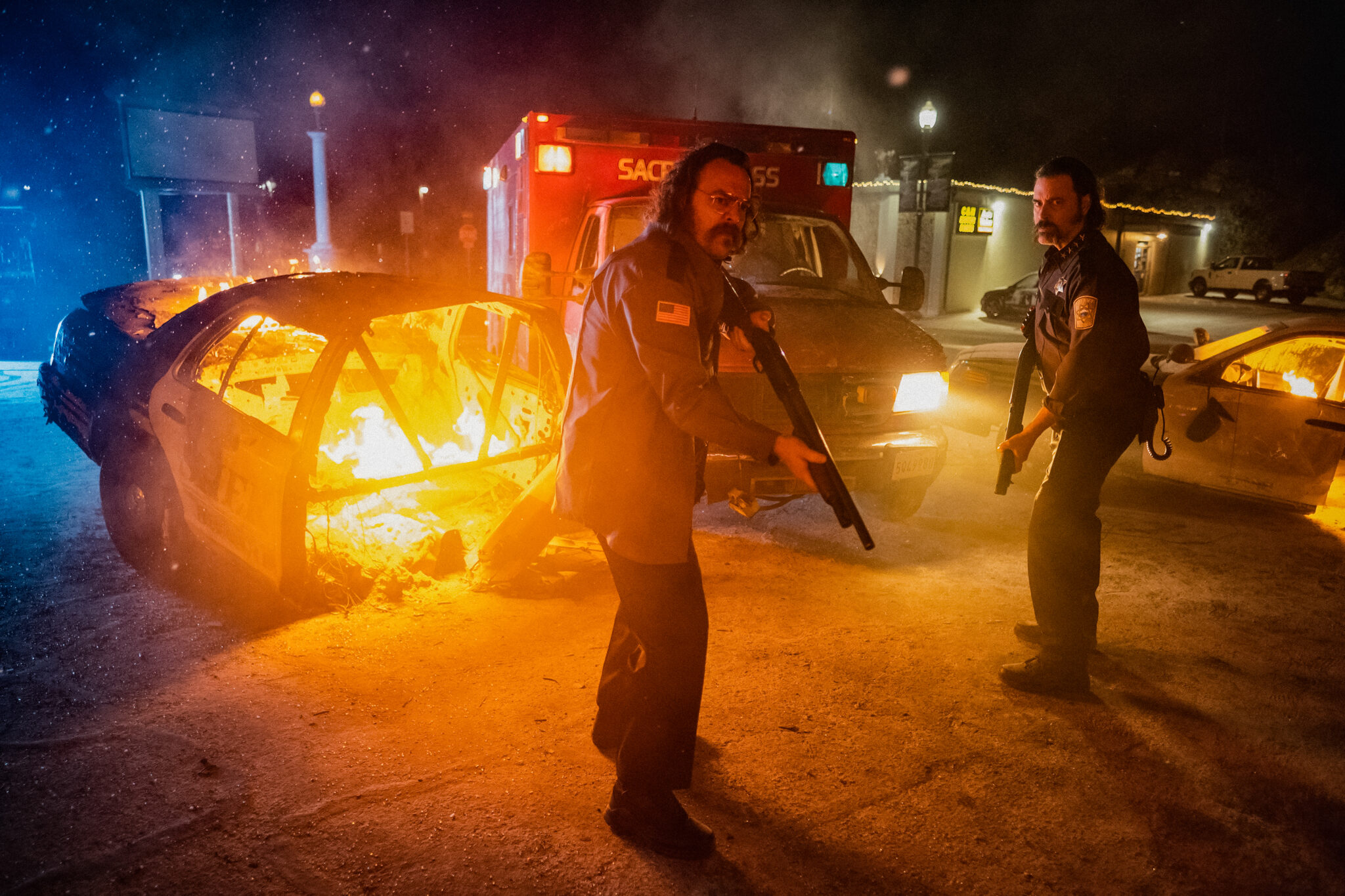 In Christmas Bloody Christmas stehen Jeff Daniel Phillips als Sheriff und Jeremy Gardner als Officer mit angelegten Schrotflinten vor den brennenden Wrackteilen eines Polizeiwagens und suchen fieberhaft in der Dunkelheit nach ihrem Feind..