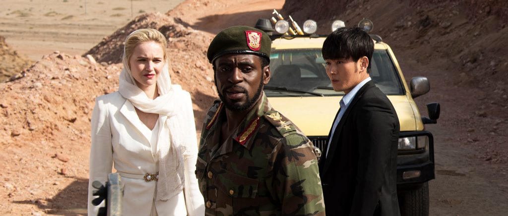 Der China Salesman, die in weiß gekleidete Blondine und auch der afrikanische Offizier stehen scheinbar ratlos vor einem Jeep in China Salesman