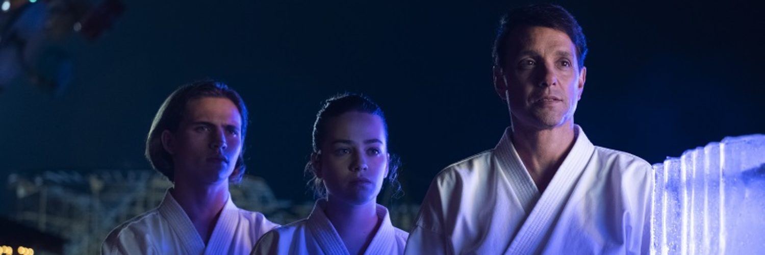 Karate-Lehrer Ralph Macchio posiert mit seinen Schülern im Neonlicht - Neu auf Netflix im August 2020