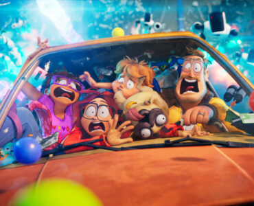 Die Familie Mitchell mit erschrockenen Gesichtern zusammengedrängt in ihrem orangen Auto. Im Hintergrund fliegen die verfolgenden Roboter heran.