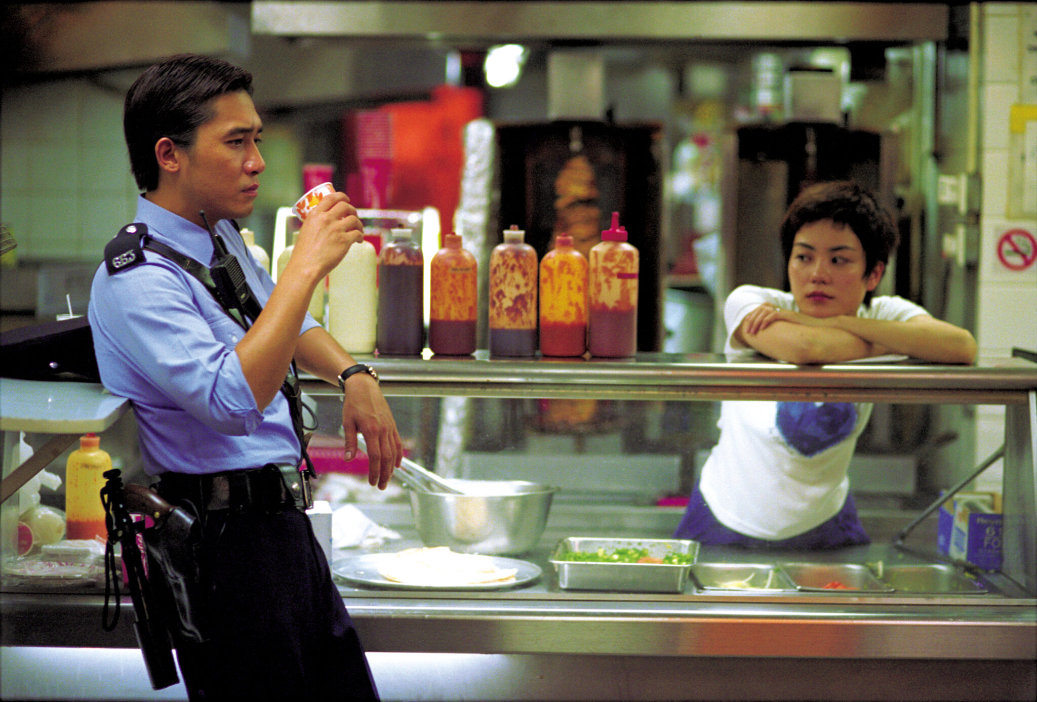 Polizist #663 trinkt in Chungking Express einen Kaffee, während Faye (Faye Wong) sich auf die Imbisstheke lehnt.