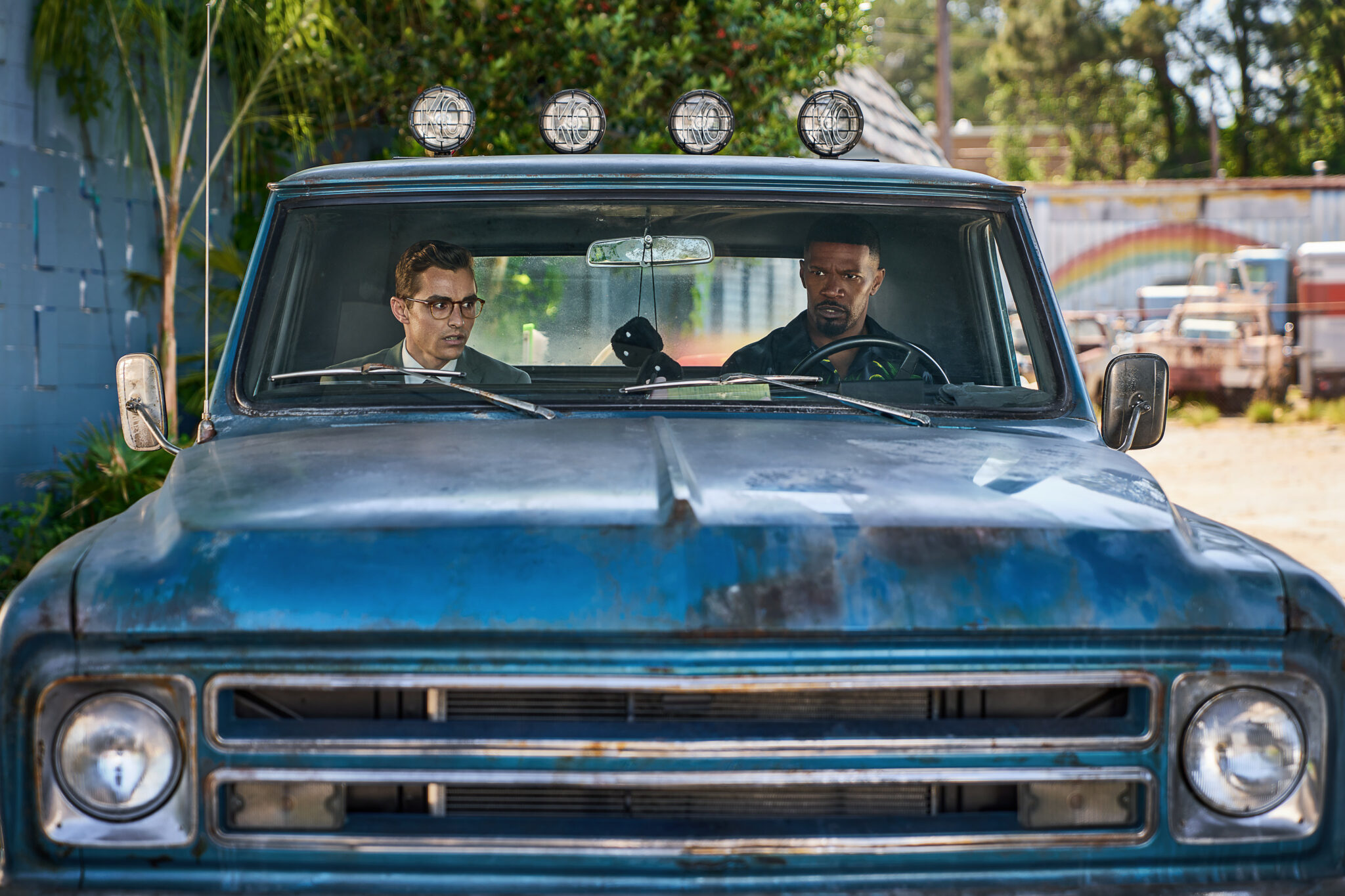 Dave Franco und Jamie Foxx sitzen zusammen in einem rostigen, blauen Truck.