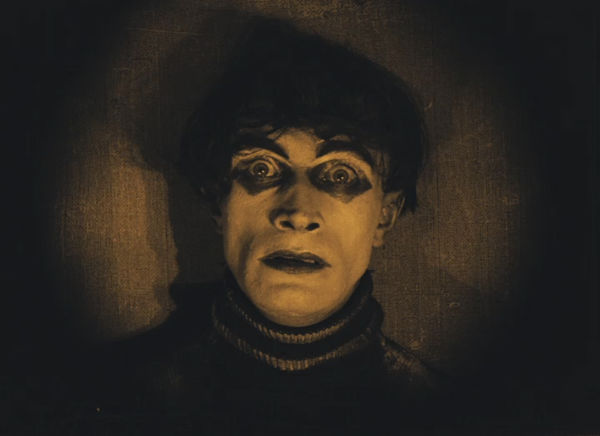 Der Somnambule Cesare blickt verängstigt vor einem dunklen Hintergrund in die Kamera.