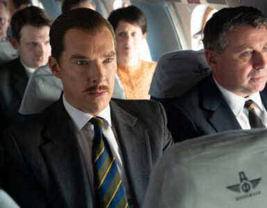 Der Geschäftsmann und Spion in spe Greville (Benedict Cumberbatch) befindet sich gerade in einem Flugzeug von Moskau zurück nach London. Er sitzt mit Anzug und Krawatte im Mittelteil der Reihe, um ihn herum sind russische Passagiere platziert.