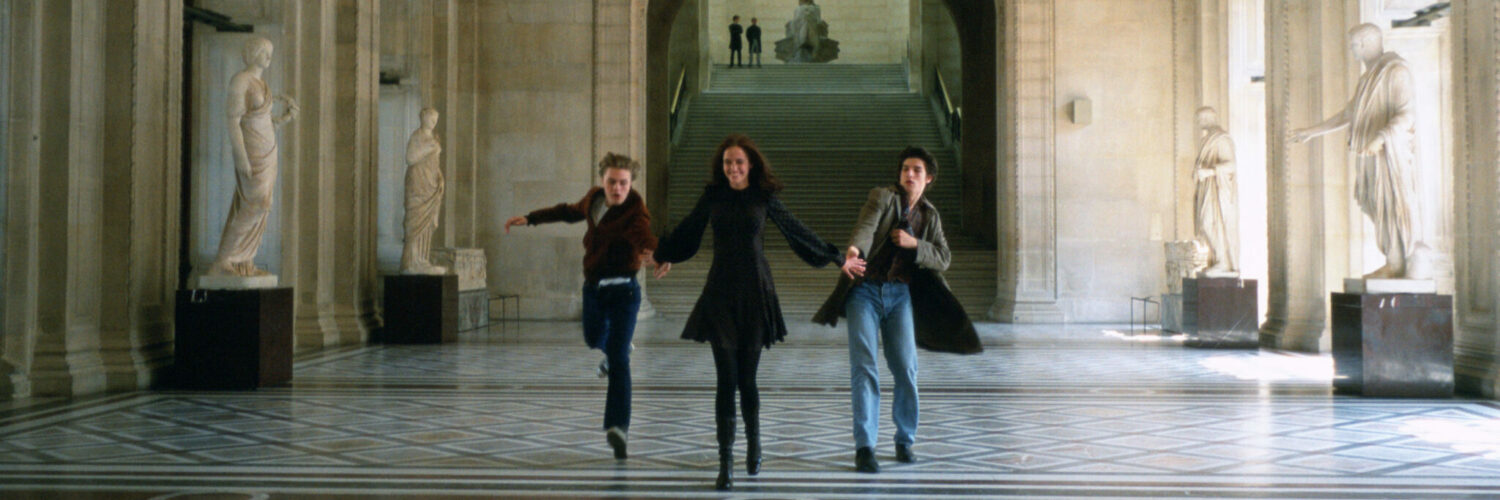 Isabelle (Eva Green), Matthew (Michael Pitt) und Theo (Louis Garrel) sprinten in Die Träumer Hand in Hand durch das Louvre, um den Geschwindigkeitsrekord aus Jean-Luc Godards Die Außenseiterbande zu knacken.