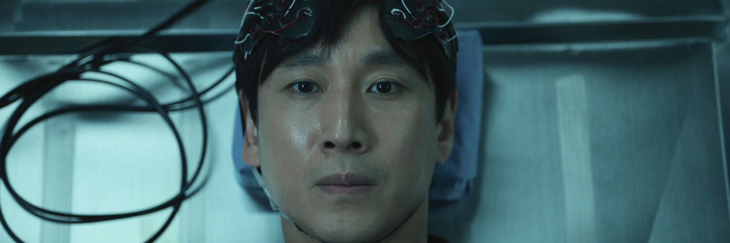 Sewon auf einer Liege mit dem Apparat zur Gedankensychronisation auf dem Kopf