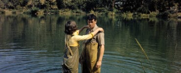 Abigail, gespielt von Paula Prentiss, und Roger, gespielt von Rock Hudson, stehen sich dicht gegenüber knietief im Wasser. Beide tragen Angelhosen, Abigail hat ihre Arme auf Rogers Schultern gelegt.