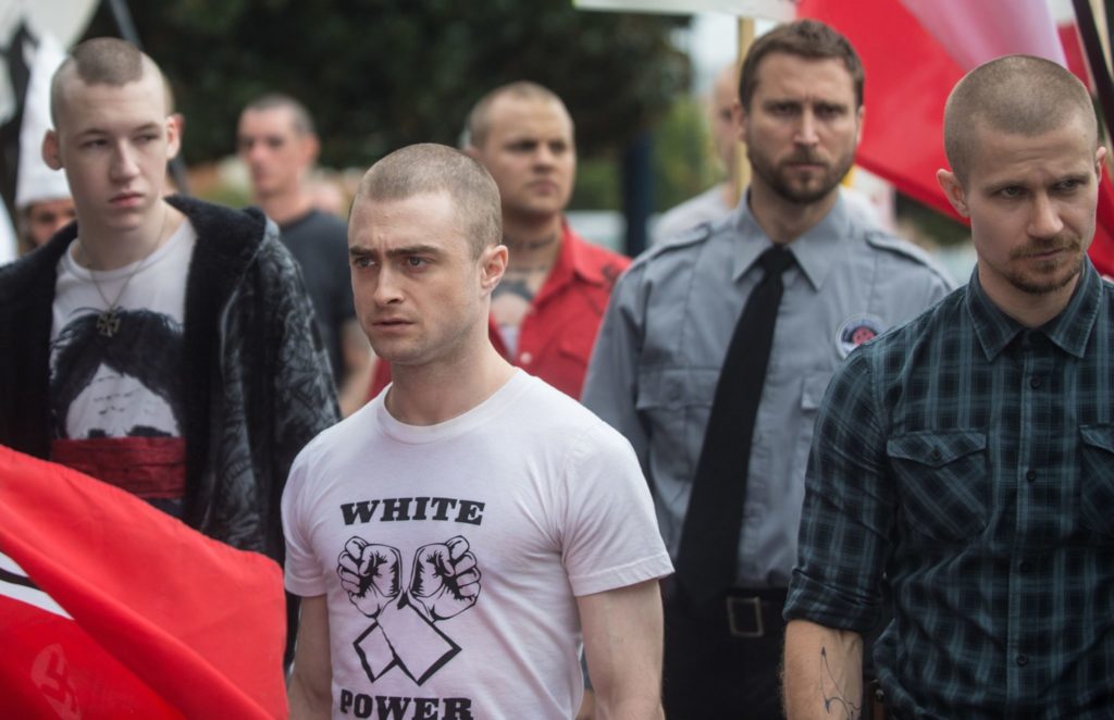 Nate steht zwischen Nazis auf einer Demonstration, er sieht unglücklich aus