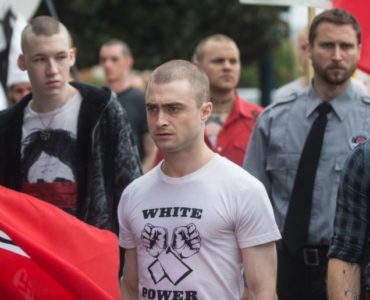 Nate steht zwischen Nazis auf einer Demonstration, er sieht unglücklich aus