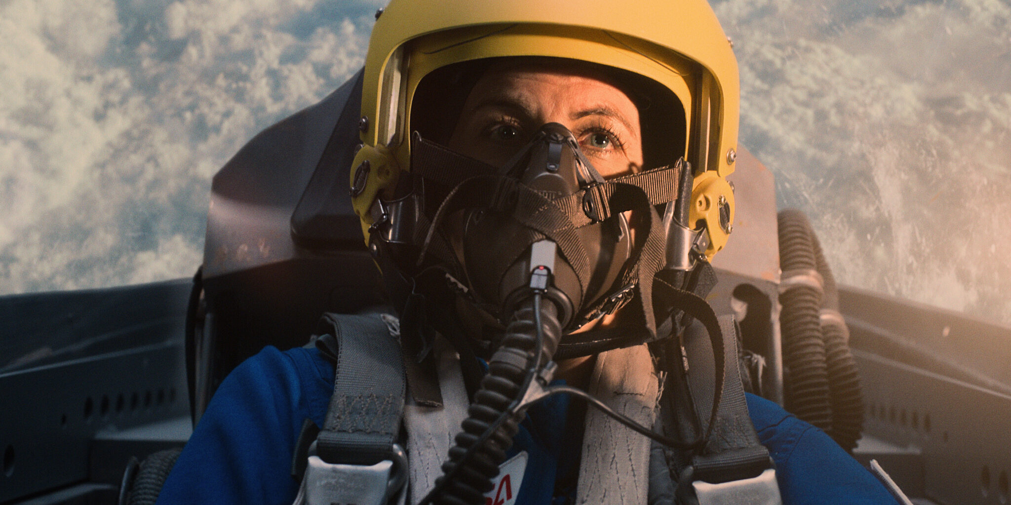 Eine Astronautin im Cockpit eines Flugzeugs mit Helm und Atemausrüstung. 