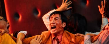 Der mit Blut überzogene Wang schützt sich und eine hyterische Frau hinter ihm vor zwei Zombies. Der Name "Get the hell out" wird Programm.