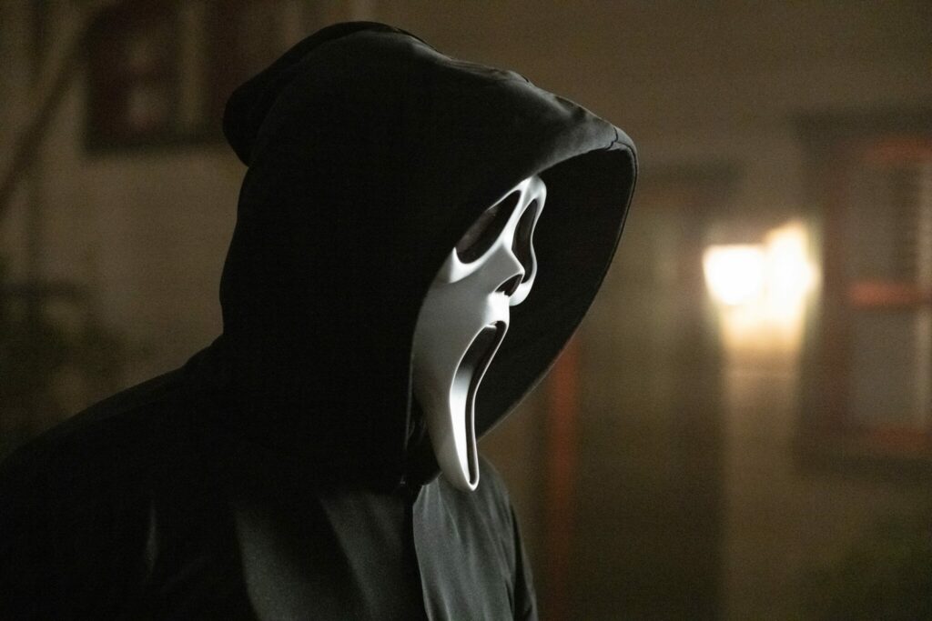 Eine Gestalt mit einer Geistermaske. Es handelt sich um den Ghostface-Killer aus dem Film Scream (2022)