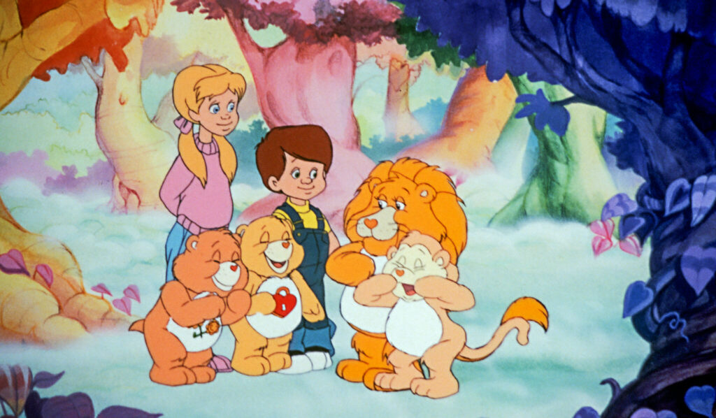Ein Junge und ein Mädchen stehen mit zwei Glücksbärchis sowie einem kleinen Löwen und Affen zusammen und lachen.