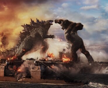 King Kong springt mit erhobener Faust auf Godzilla zu, während sich beide auf einem Flugzeugträger befinden.