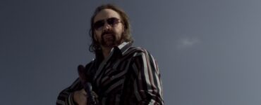 Walter (Nicolas Cage) steht mit Sonnenbrille und Gewehr auf dem Dach und blickt hinab zu seinem potentiellen Opfer.