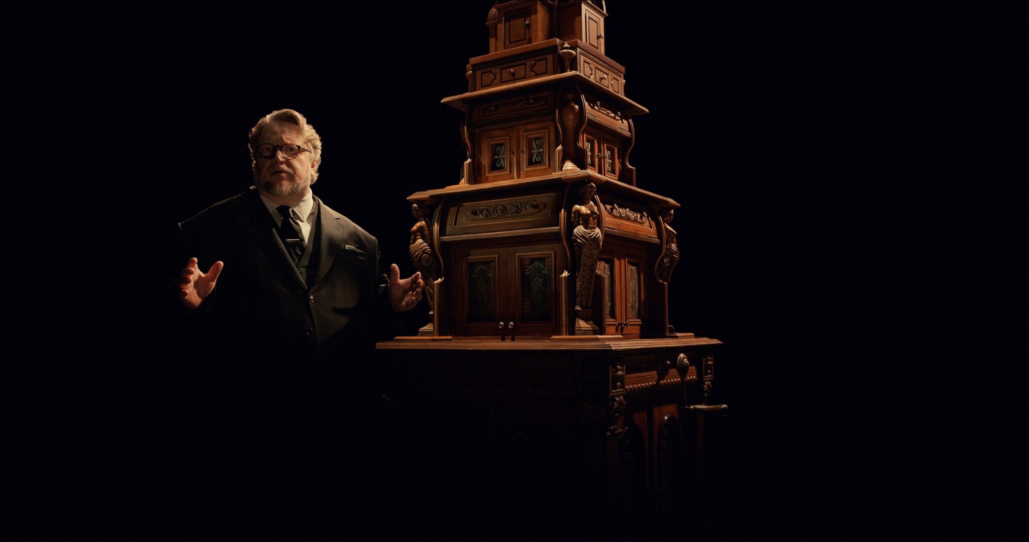 Guillermo del Toro neben einem Kabinett aus Holz. Cabinet of Curiosities