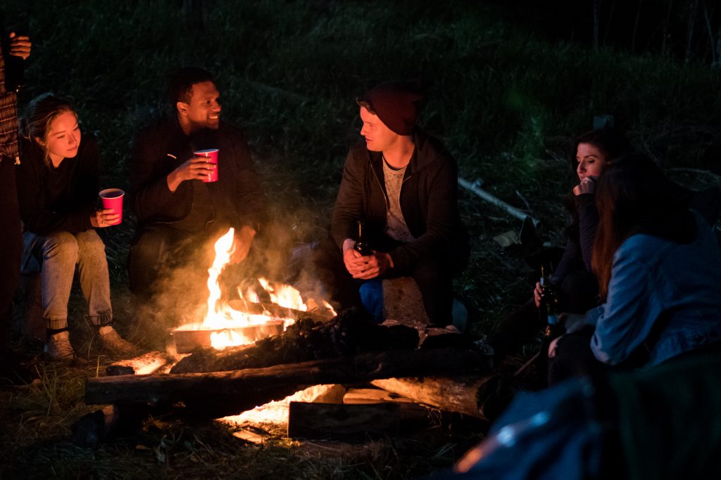 Die Freunde sitzen am Lagerfeuer und trinken Alkohol, haben Spaß in Slasher: Guilty Party