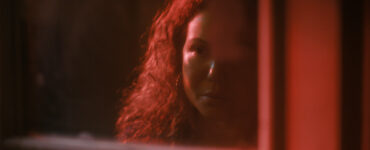 Im Halbschatten des Rotlichts sieht man Dolores Roach hinter einer Fensterscheibe - Neu bei Prime im Juli 2023