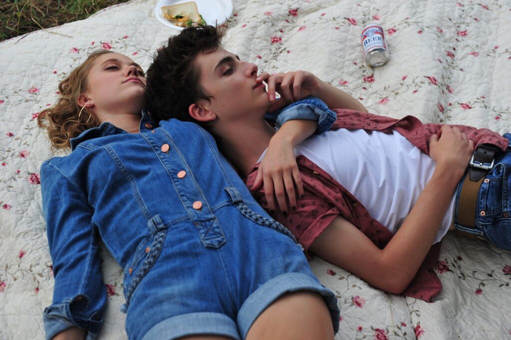 Timothée Chalamet liegt in Hot Summer Nights auf einer Picknickdecke in den Armen von Maika Monroe.
